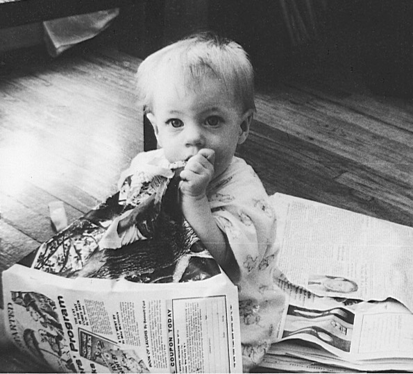baby eating newspaper